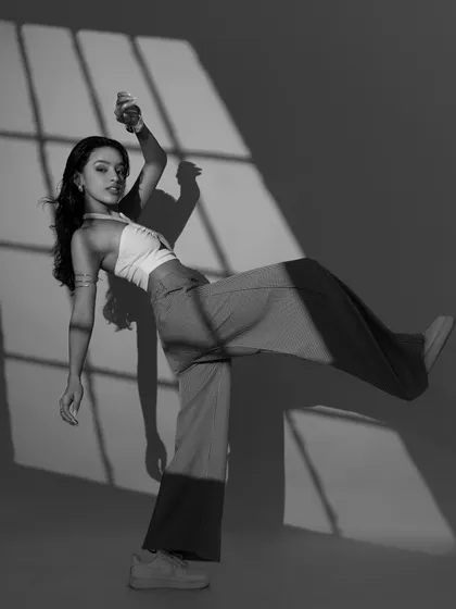 A black and white take on a dynamic, high-kick pose. The contrast highlights the shape and energy of the movement against the stark background.