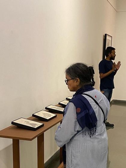 An older visitor contemplates the small works.