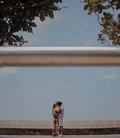 A creatively framed shot of Ashleen and Ranjodh against the open sky and sea at Marine Drive. Using a foreground element creates a unique and artistic composition for this pre-wedding portrait.