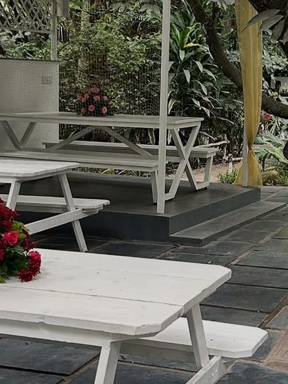 For casual outdoor seating, we provide picnic-style tables. Here, we've kept the decoration simple with a small, elegant centerpiece of red roses on each white table.