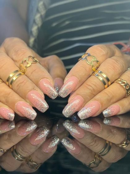 A glamorous set of long, square-shaped nails with a pink and silver glitter ombre effect.