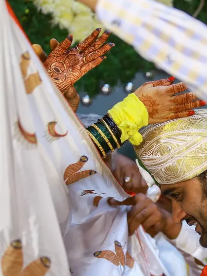 The Antarpat ritual, where a cloth separates the bride and groom before they see each other. We capture the anticipation and the beautiful details, like the bride's henna-adorned hand.