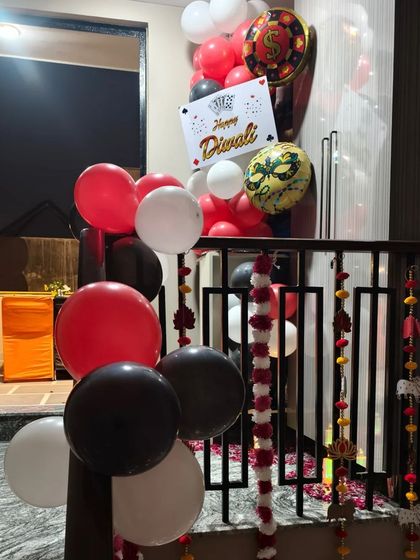 A balloon pillar with a "Happy Diwali" sign and casino-themed foil balloons, placed at the entrance of the party.