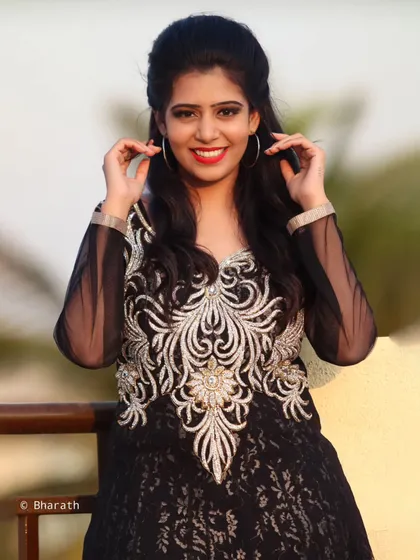 A three-quarter shot of the model in the black gown, showing the intricate silver embroidery on the bodice.