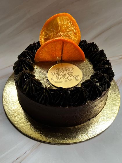 A simple yet elegant design for a birthday. This Drunken Zesty Belgian Chocolate cake is topped with a single candied orange slice and a "Happy Birthday" plaque.