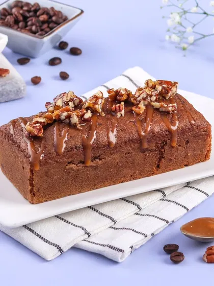 A close-up of the Coffee Pecan Teacake, showing the rich caramel drizzle and the texture of the toasted pecans on top.