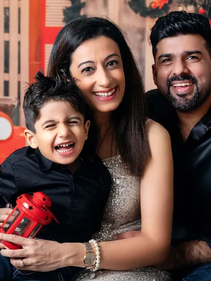 A beautiful family portrait full of laughter. The red lantern adds a perfect pop of festive color to their stylish black and silver outfits.
