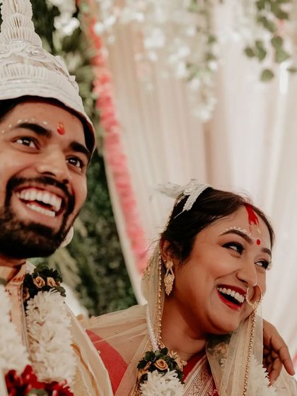 A moment of pure, uninhibited laughter between the bride and groom during their Bengali wedding.
