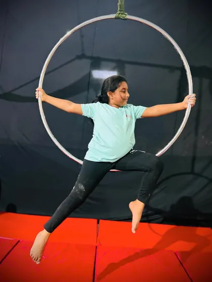 A powerful and confident pose, this young student sits poised in the aerial hoop, ready for her next move.