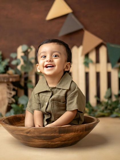 A cute little "range officer" sitting in a wooden bowl in his rustic first birthday setup.