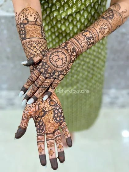 A playful pose showing off the engagement mehendi, which features both peacocks and a ring motif.