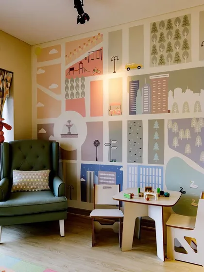 I love creating dedicated zones for different activities. This little corner features a child-sized table and chairs set against a playful city-map wallpaper, perfect for drawing and crafts.