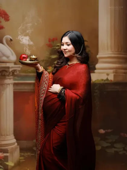 A solo portrait of a mother-to-be in a deep red saree, holding a diya. This image beautifully captures the spiritual and cultural aspects of motherhood.