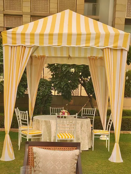 A close-up of a private dining cabana from the brunch setup. The yellow and white stripes, combined with elegant seating, create a perfect spot for an intimate meal.