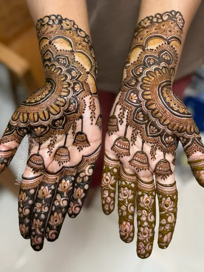 The rich, dark henna paste brings out the details in this engagement design. The combination of mandalas, lotuses, and jhumkas creates a complete and festive look.