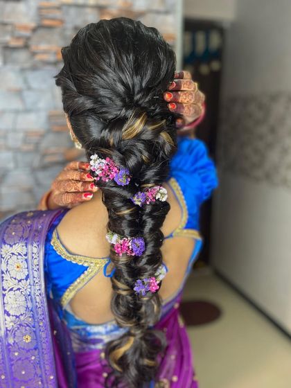 A close-up of the floral braid, showing how the flowers are carefully tucked into the plait. This style is perfect for an engagement or sangeet, adding a touch of color and romance.