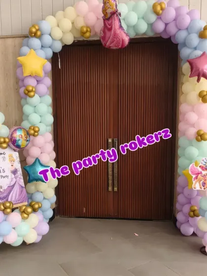 The entrance to the party room, decorated with a pastel balloon arch and princess cutouts.