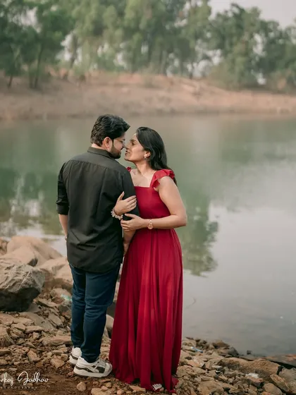 An almost-kiss by the water. This intimate shot from behind the groom focuses on the couple's closeness and the beautiful, serene environment of their pre-wedding location.