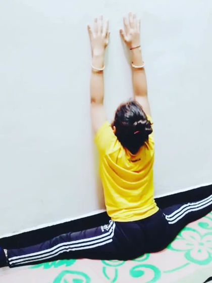 Another view of a wall-assisted middle split, this time with arms reaching up to deepen the stretch in the torso. Continuous improvement is always better than delayed perfection.