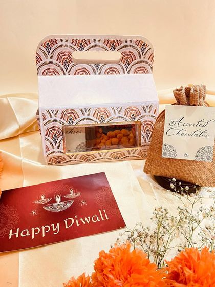 A simple yet elegant Diwali favor, this patterned carrier box is paired with a burlap pouch of assorted chocolates, making it a lovely small gift.
