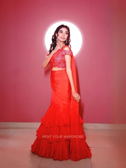 A classic pose against a simple backdrop, letting the vibrant red saree be the hero of the shot.