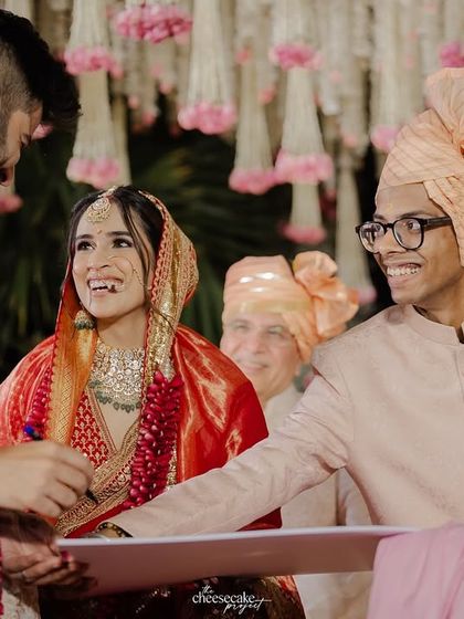 A close-up of the groom signing the contract, with the bride and a friend looking on with big smiles.