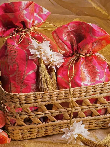 This shot features beautiful brocade potli bags in a rustic wicker basket. The mix of textures and the soft, warm lighting create a rich and inviting image.