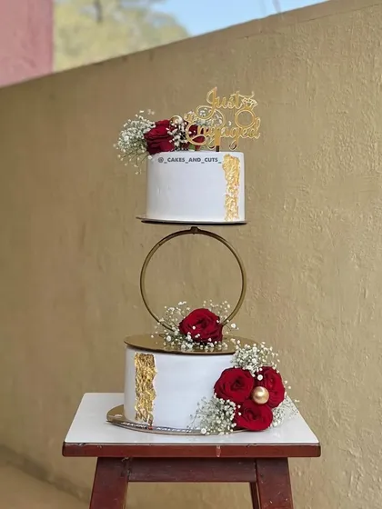 We love being part of new beginnings. This two-tier engagement cake features a delicate gold hoop separator and is adorned with fresh red roses and baby's breath. You can learn how to properly prep and place fresh florals on cakes for a food-safe and beautiful finish.