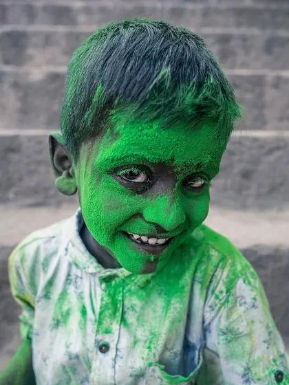 A child's face, covered in bright green powder, breaks into a joyful smile during the Holi festival in Vrindavan, the city of colors.