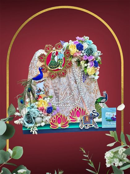 This Teej gift presentation features a beautifully draped saree, accented with peacock motifs and a vibrant mix of flowers. The design is both traditional and eye-catching, perfect for the festive occasion.