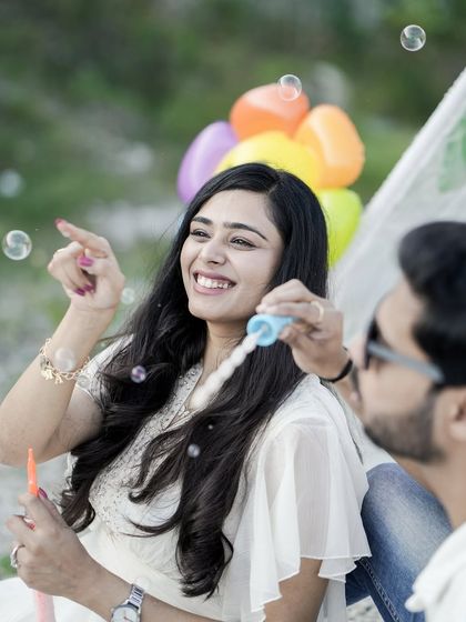 A close-up of the bride's joyful laugh as she plays with bubbles during a fun, outdoor pre-wedding picnic.