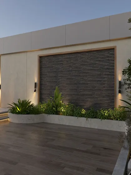 This detail of the terrace shows the built-in planters and a feature wall with wooden slats. The strategic use of up-lighting creates a sophisticated ambiance in the evening, highlighting the textures of the plants and materials.