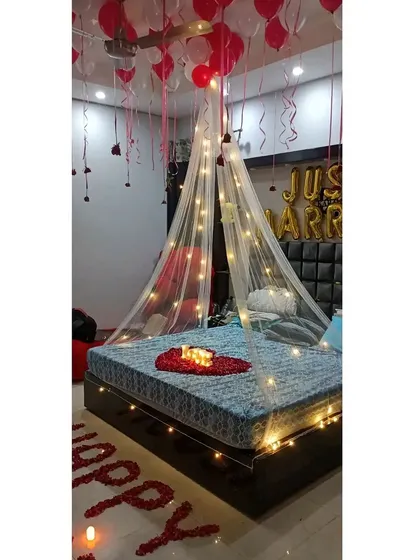 The complete "Just Married" setup, showing the relationship between the ceiling balloons, the bed canopy, and the rose petal message on the floor.