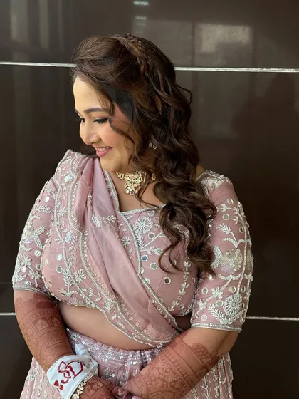 A side profile showing the beautiful braided detail in her hair and the soft curls. The hairstyle perfectly complements her elegant baraat look.