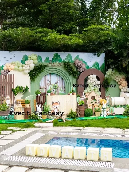 Advaith's woodland adventure set against a beautiful poolside backdrop. This outdoor party decoration shows a full-stage setup with a custom arched backdrop, 3D animal cutouts, hot air balloon props, and lush greenery, proving that any space can be transformed into a fantasy.