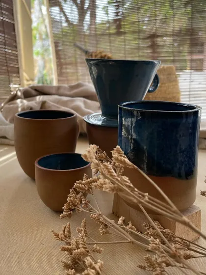 A collection of my handmade ceramic mugs, each with its own unique shape and glaze. The little coffee bean detail on the handle is a fun touch for coffee lovers.