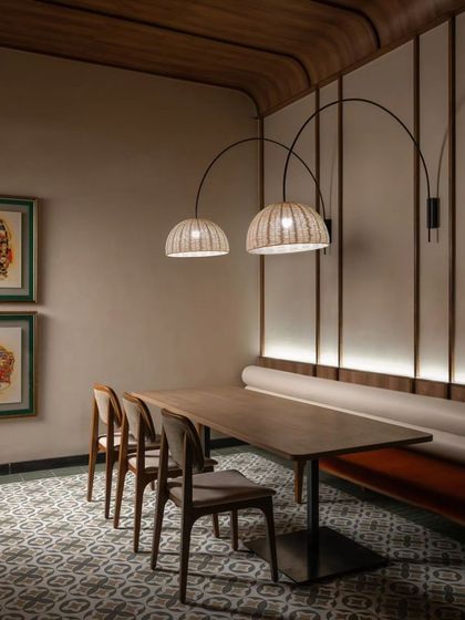 This dining setting combines a long upholstered bench with individual chairs, illuminated by elegant arched pendant lamps. The design offers flexibility for different group sizes while maintaining a cohesive and stylish look.