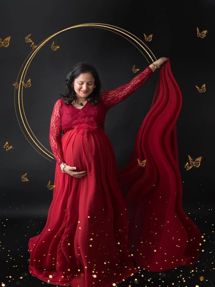 A beautiful and artistic portrait in a red lace gown. The golden butterflies and sparkling effects add a touch of magic and whimsy to this maternity photo.