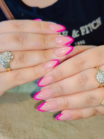 A bold and beautiful French manicure. The almond-shaped nails are given a modern update with a striking hot pink tip, perfect for making a statement.