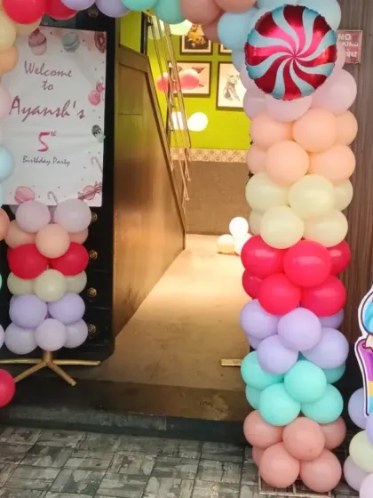 The entrance to the Candyland party, decorated with a pastel balloon arch and large candy and cupcake cutouts.