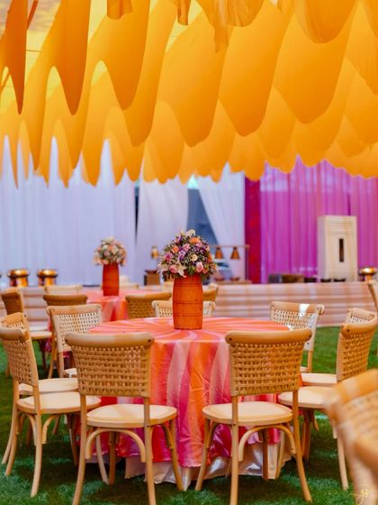 A close-up of the table setting, featuring a striped tablecloth and a rustic orange vase with a colorful floral arrangement, perfectly matching the Haldi's theme.