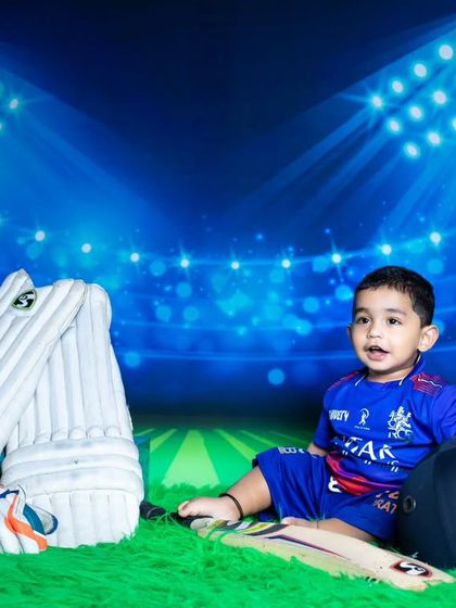 This little RCB fan is ready for the IPL season, dressed in a cricket jersey with a bat and pads.