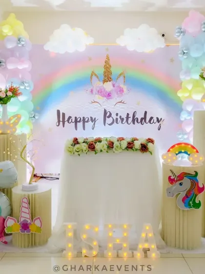 A dreamy unicorn party for Isra, featuring a rainbow backdrop, cloud cutouts, and a large inflatable unicorn.