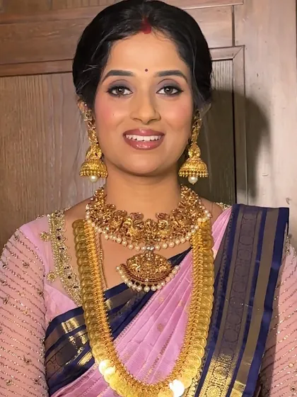 A beautiful portrait of Raksha. This look features a classic combination of a pink and blue silk saree, traditional gold jewellery, and makeup focused on defined eyes and a radiant complexion.