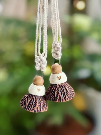 These ceramic ornaments are designed to look like little dolls with carved skirts. They add a unique, handmade touch to any Christmas tree.