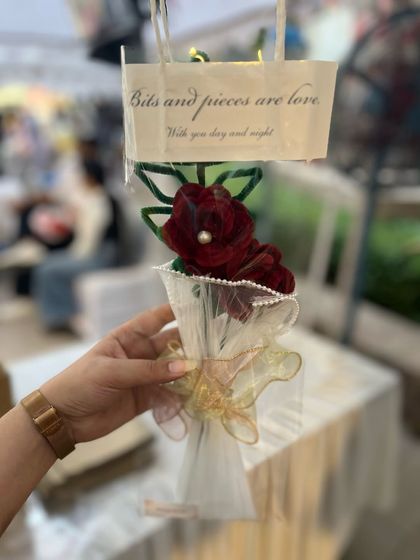 A beautifully packaged single red rose, perfect for gifting. The little tag says "Bits and pieces are love," which is exactly what our craft is about.