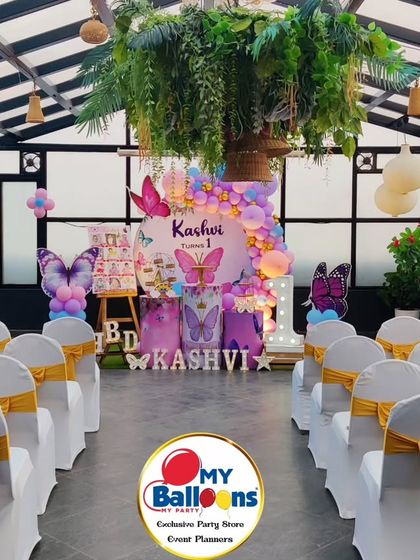 A wide shot of a butterfly-themed first birthday, showing the full setup with guest seating. The rooftop venue adds a special touch.