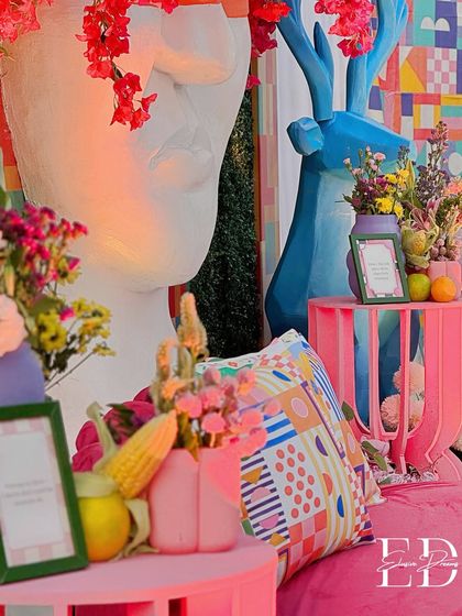 Details from the carnival theme, showcasing a mix of textures and bright colors. A large abstract face sculpture, a blue deer, and colorful cushions create a surreal and artistic vibe.