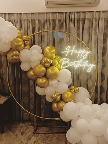 A simple and elegant white and gold balloon ring. This setup is perfect for a sophisticated celebration and can be placed in front of curtains or a plain wall.