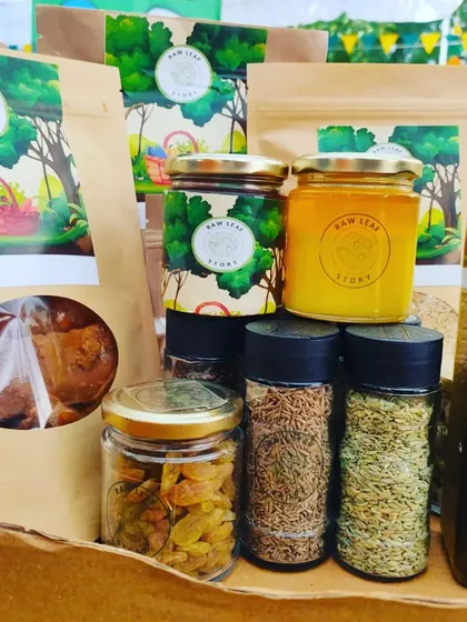 A collection of our organic pantry products. This includes pouches of dried goods, jars of raw honey and spices like cumin and fennel seeds, and bottles of cold-pressed oil.